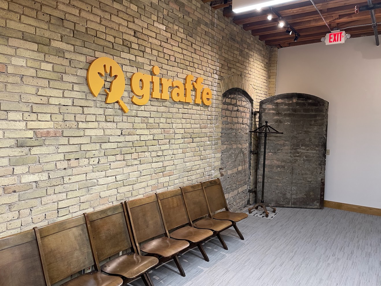Giraffe logo sign mounted on exposed brick above waiting room chairs