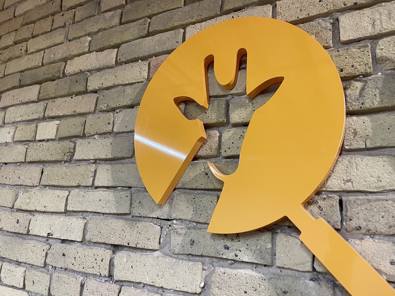 Close-up of the orange Giraffe logo sign mounted on exposed brick