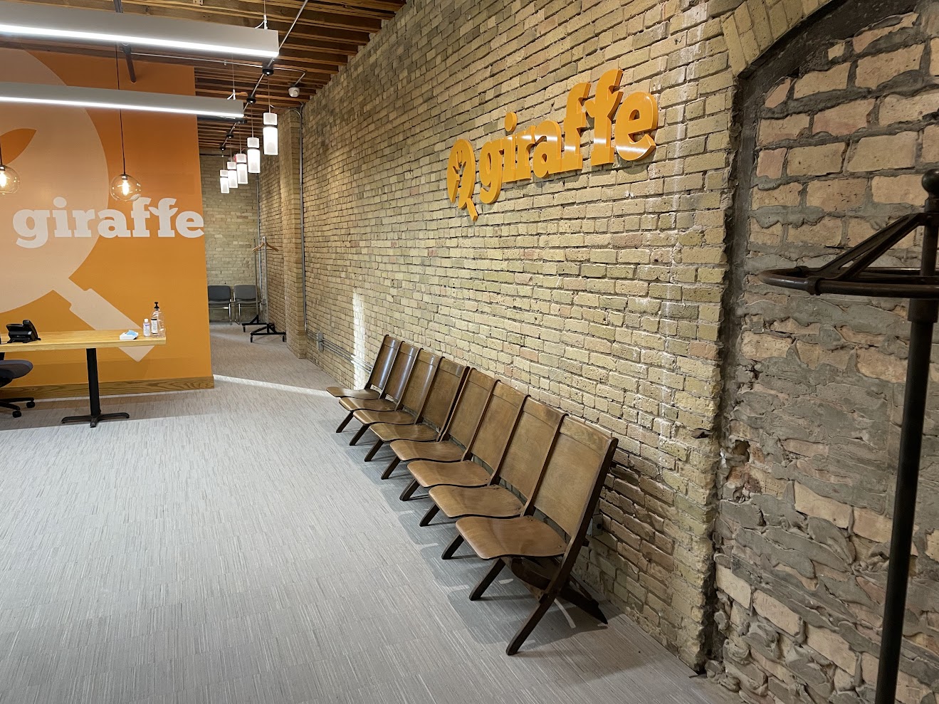 Hallway view of the Giraffe office with orange branding and brick walls