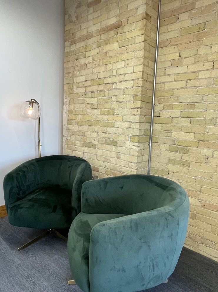 Green velvet lounge chairs against exposed brick wall